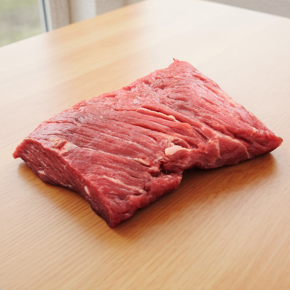 Rohes Rindfleisch-Stück auf hellem Holztisch