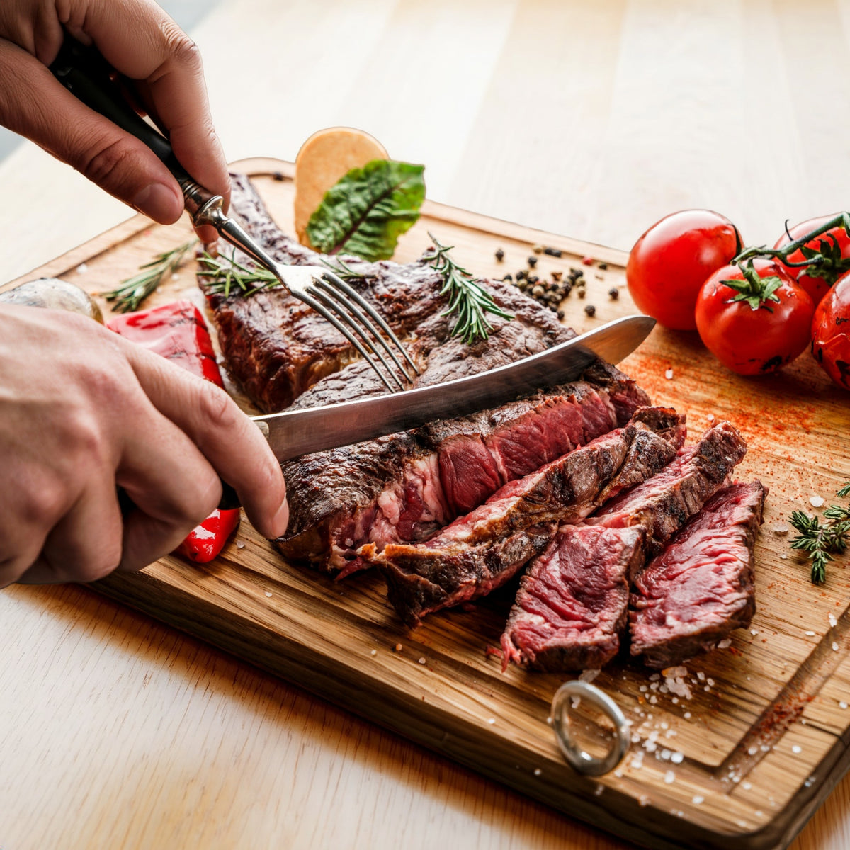 Tomahawk-Steak wird auf Holzbrett angeschnitten